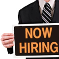 Man holding Now Hiring sign