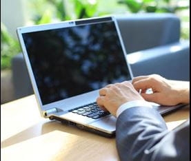 fingers on keys of a laptop with blank screen