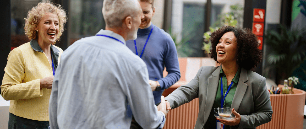 A woman shaking hands with a man while smiling at an event