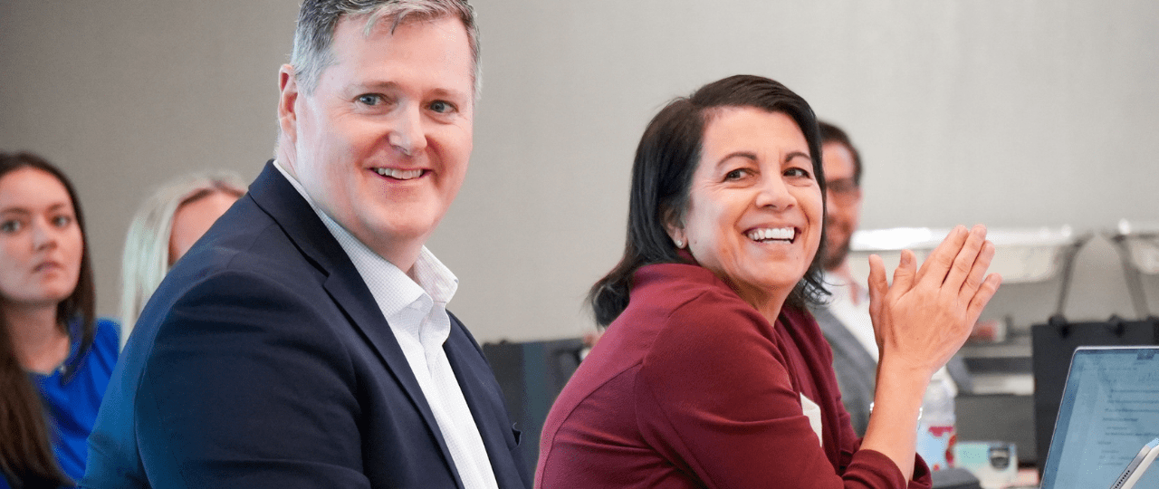 A man and woman sat at a table smiling and clapping