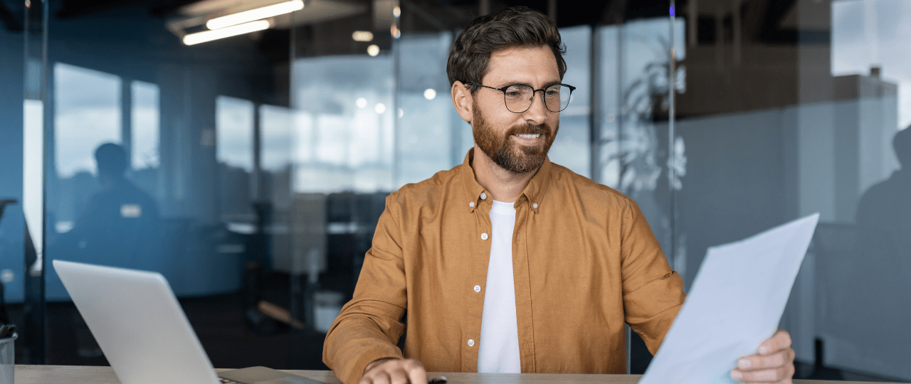 A man sat at a desk looking at a piece of paper