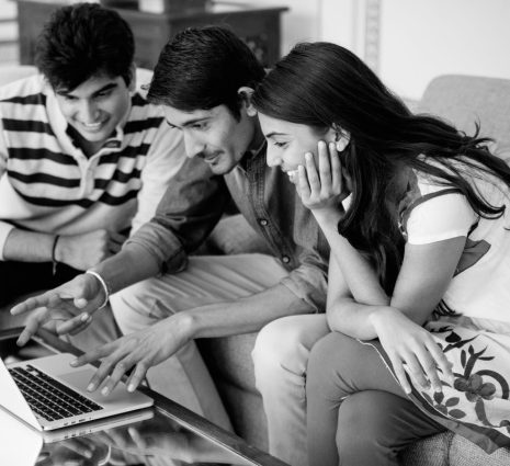 Three students looking at a laptop and smiling