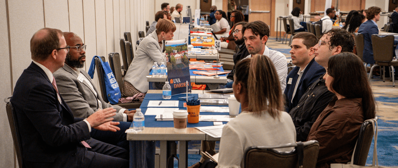 A group of students sat at a table talking to school professionals at a recruitment event