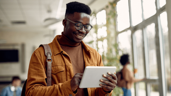 A young man smiling looking at his tablet device