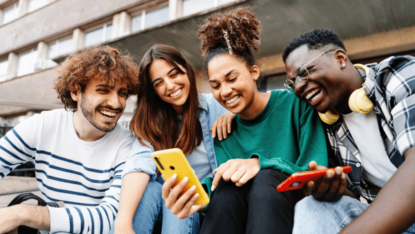 Four students huddled together taking a picture on their phone