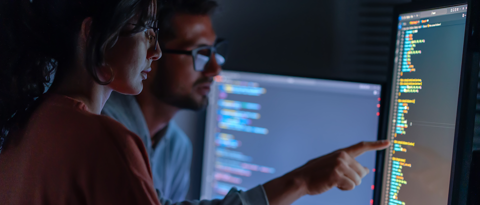 Two people looking at code on a computer screen together