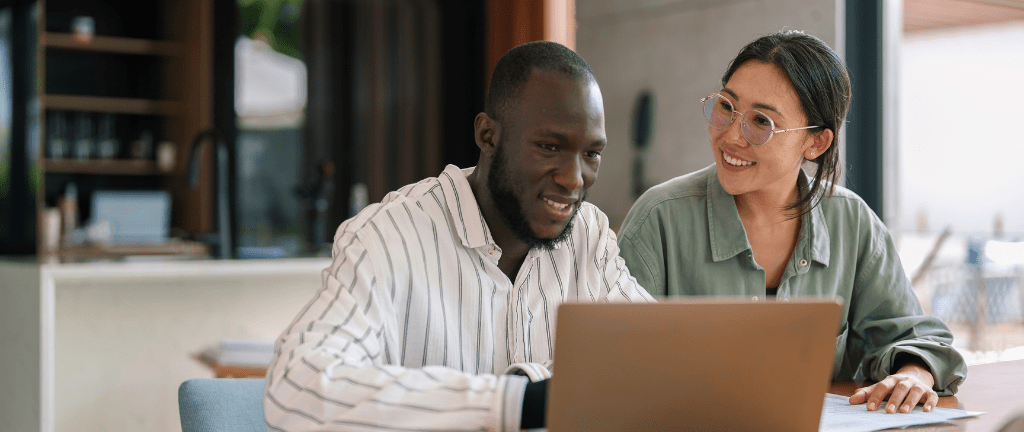 Man and woman smiling while looking at a computer screen together