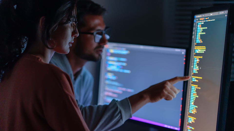 two people looking at code on computer screen together