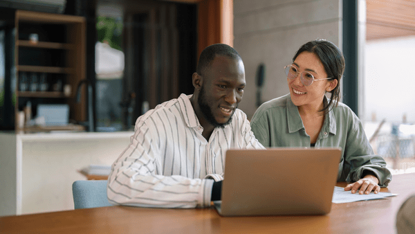 Man and woman smiling while looking at a computer screen together