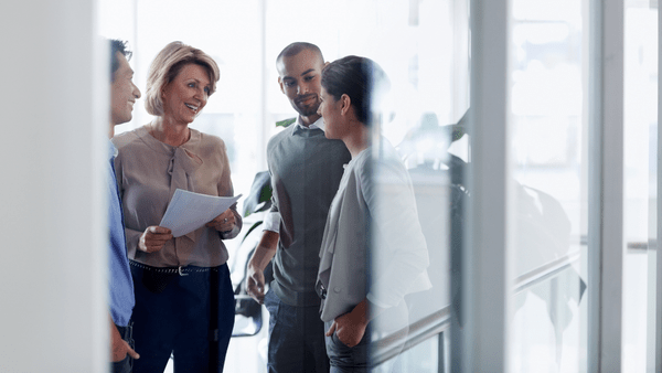 A group of people in conversation holding documents