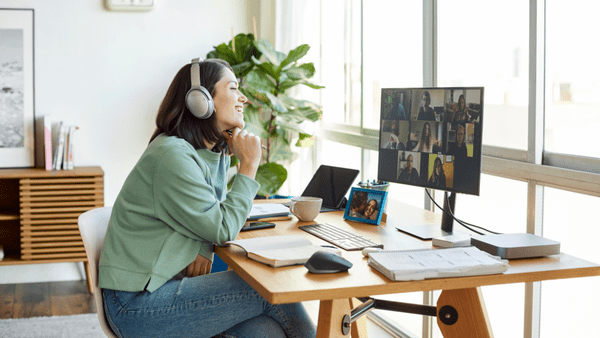 Woman with headphones sat at a desk on a video call