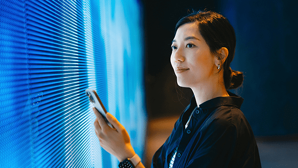 woman-with-cell-phone-in-front-of-blue-light-wall