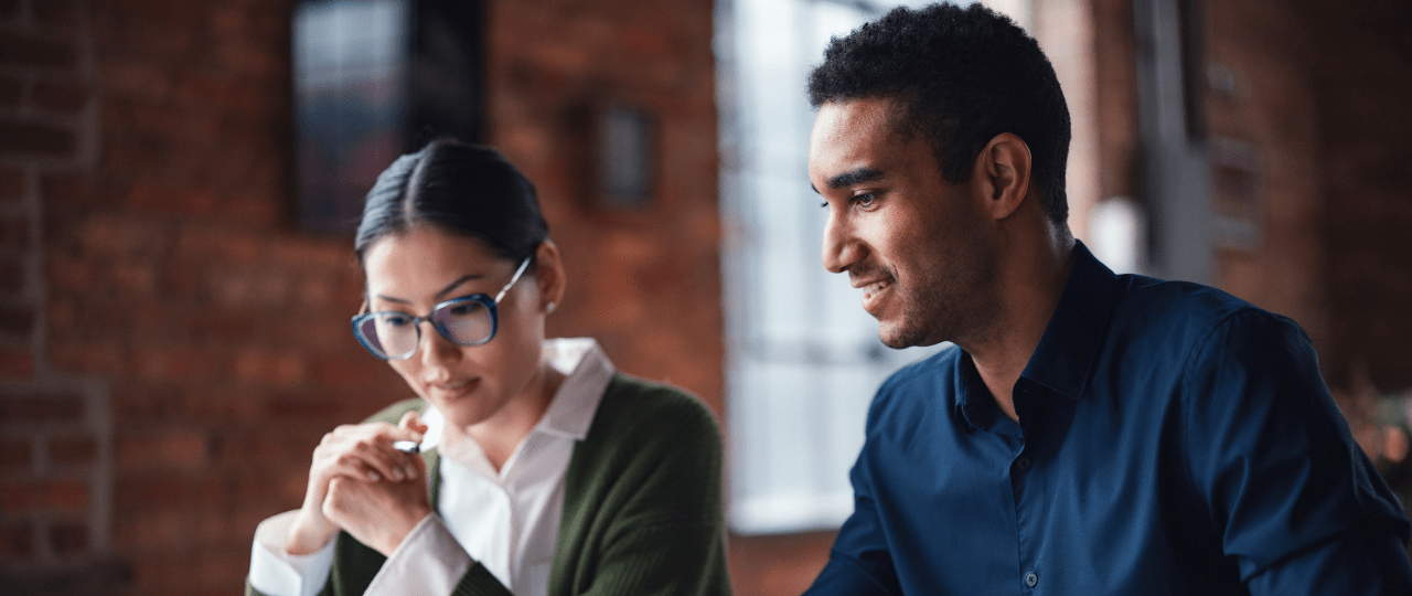 Man and woman smiling while looking at a computer