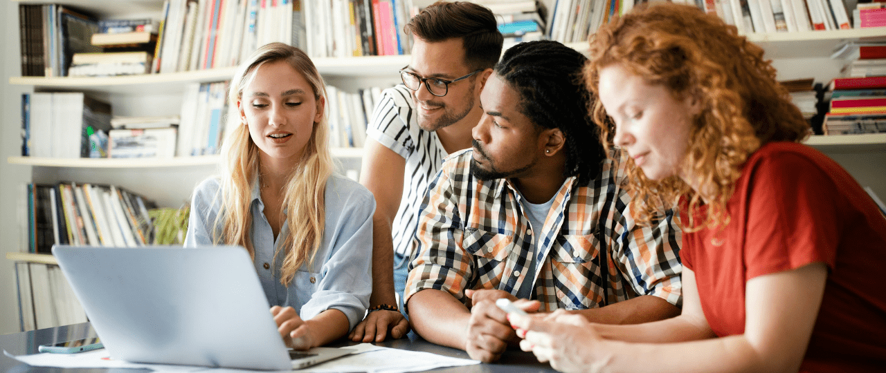 Group of coworkers sitting a desk looking at a laptop