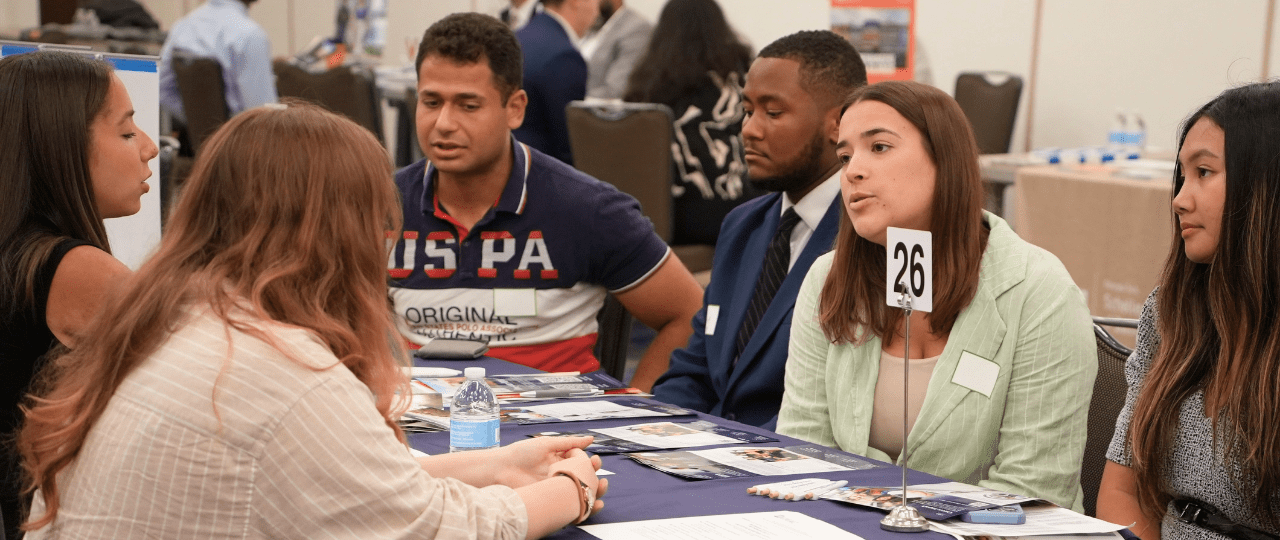 A group of students sat around a table talking to two school professionals