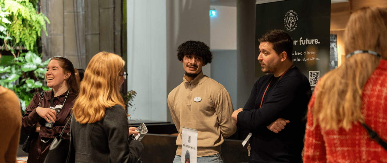 A group of people smiling and talking at a recruitment event