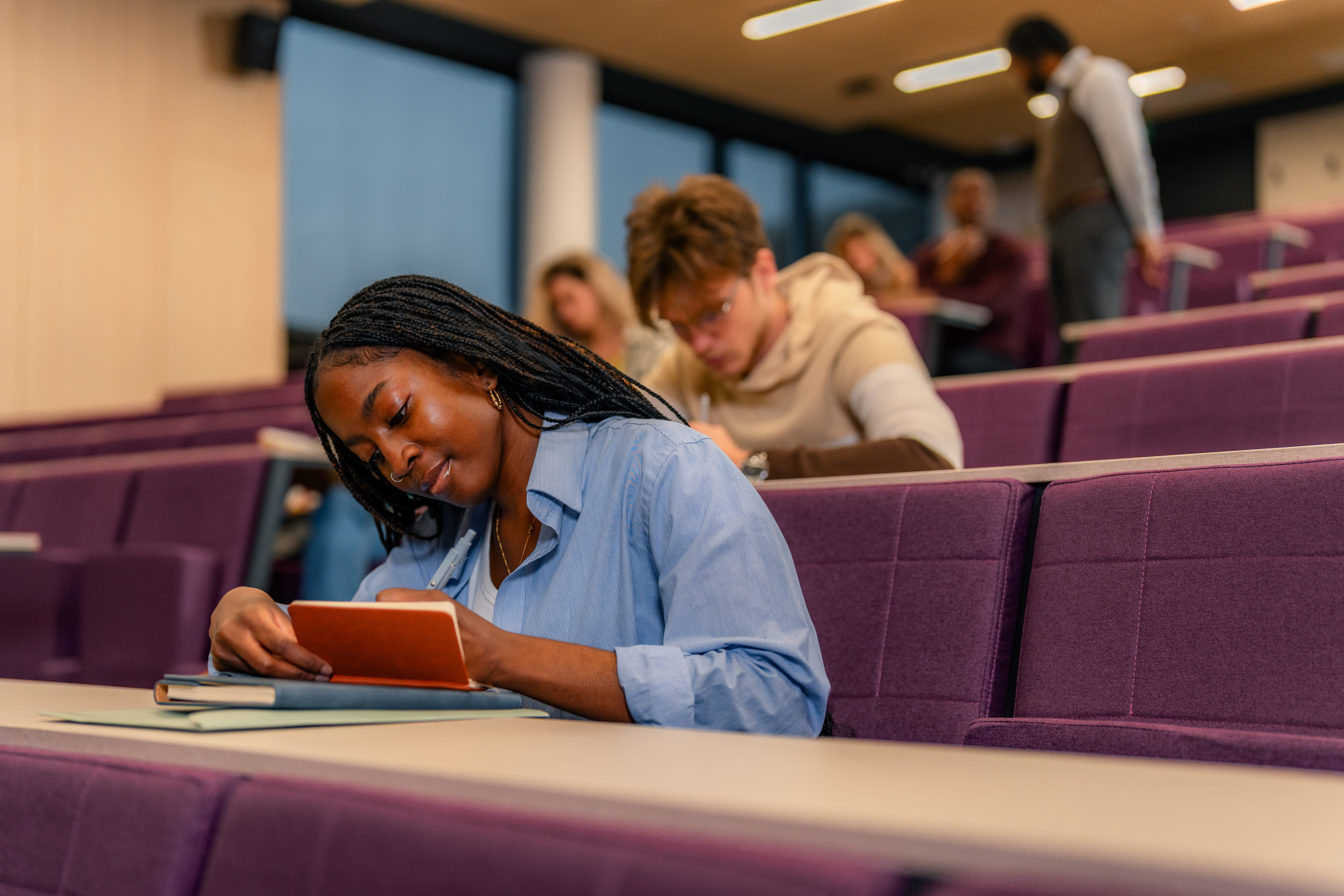 Woman takes notes in lecture style classroom
