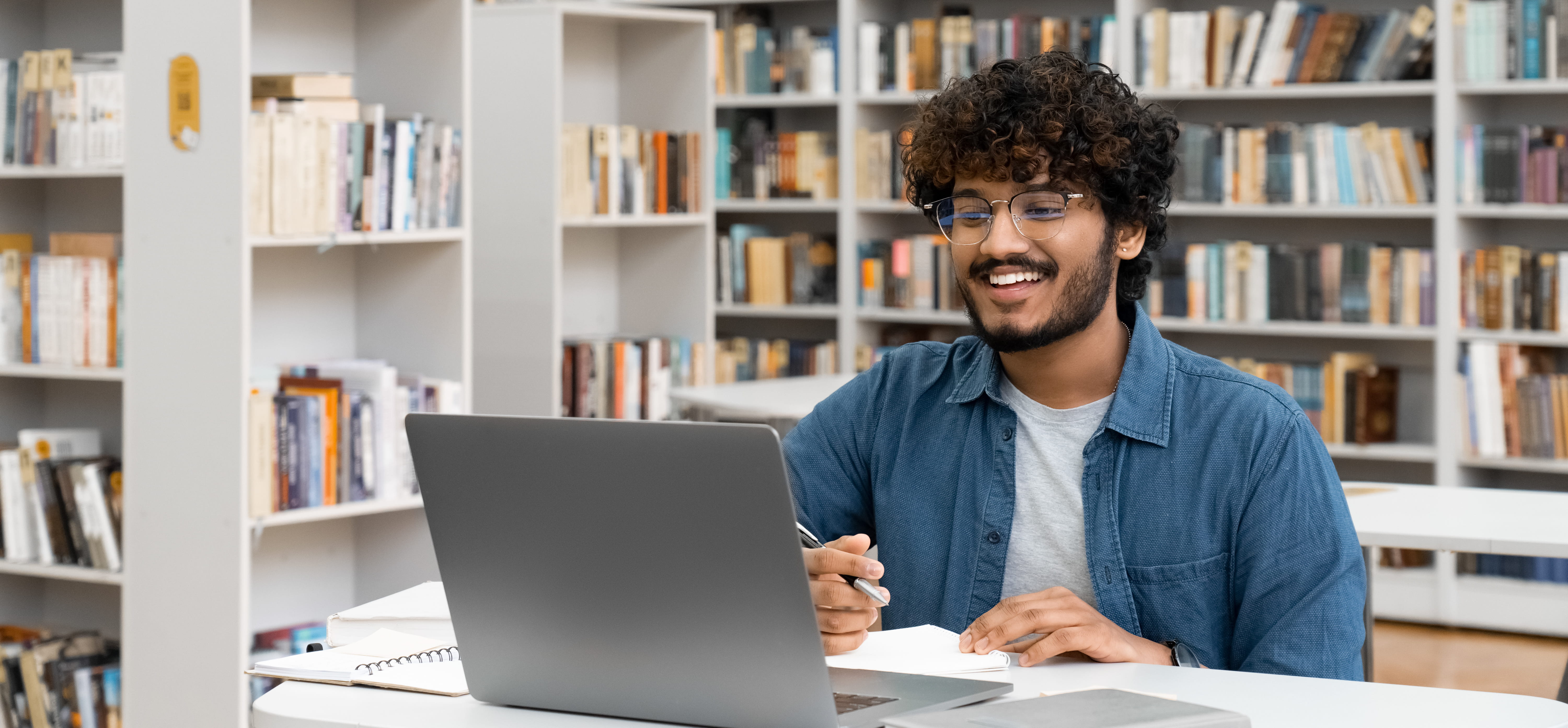 Man sits behind computer in a library