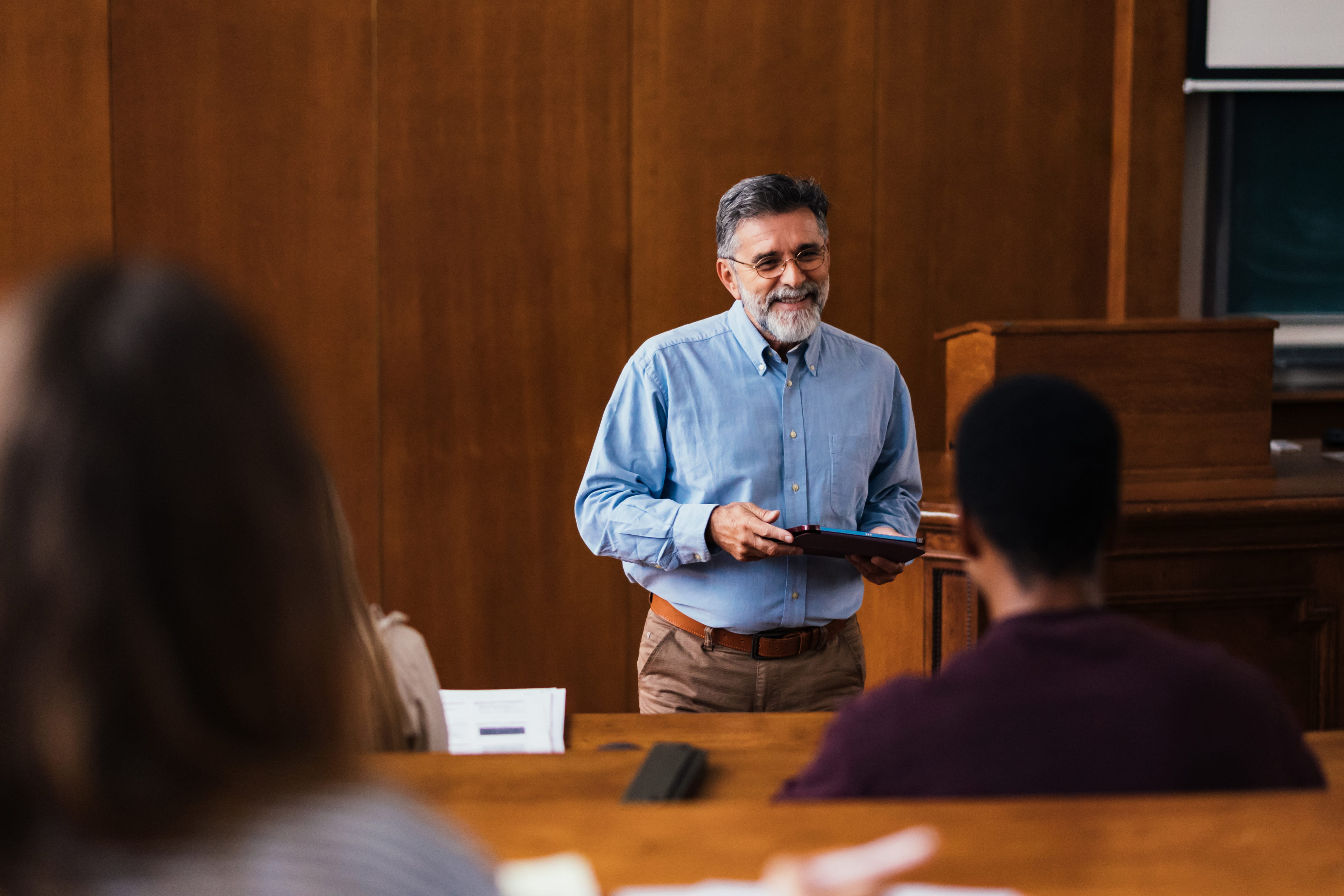 Man in blue shirt lecturing in front of a class