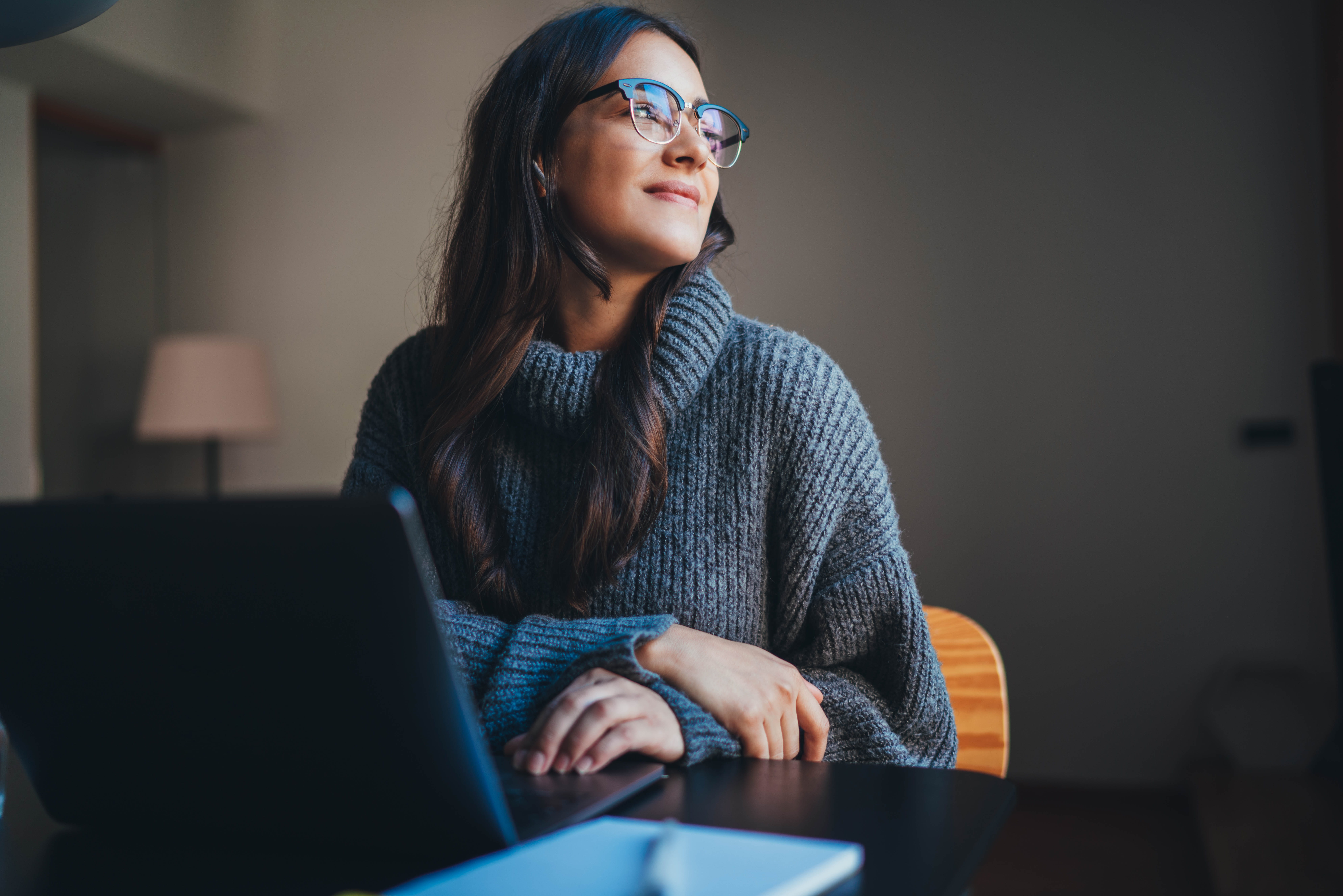 Smiling women sat at a desk in front of a laptop 